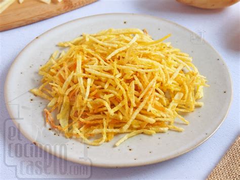 Patatas paja recién fritas escurriéndose en papel absorbente