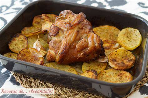 Codillo de cerdo asado en bandeja de horno con patatas y cebolla