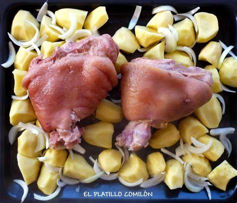Codillos de cerdo sobre patatas y cebolla listos para hornear