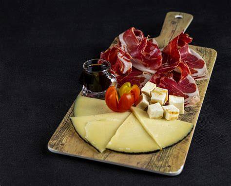 tabla de jamón ibérico con diversos quesos