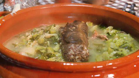 Puchero de berza con morcilla, chorizo y costilla humeante en un plato rústico