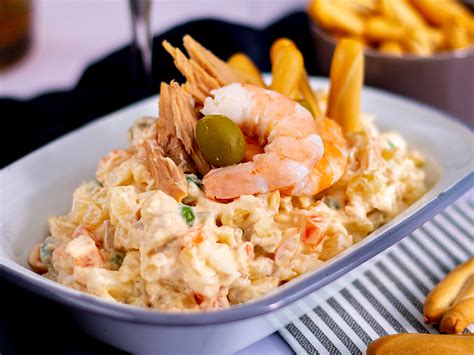 Ensaladilla rusa servida en una fuente elegante con decoración de langostinos