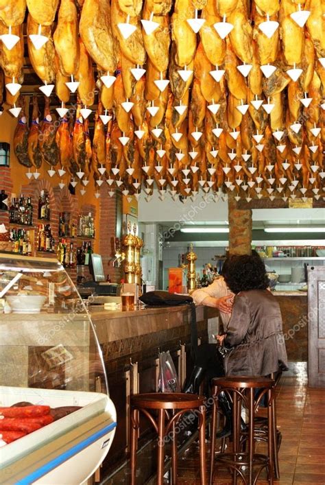Interior de El Buen Jamón con jamones colgando y zona de barra