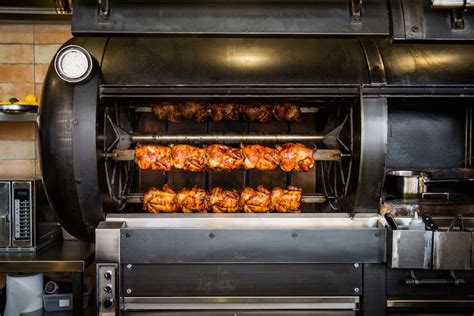 Asador de pollos y carnes a la brasa en restaurante mediterráneo