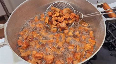 Javier González elaborando chicharrones en una gran olla