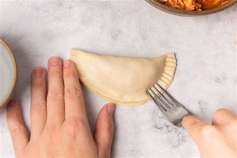 Proceso de sellado de empanadillas con un tenedor