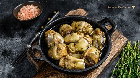 Alcachofas confitándose en aceite de oliva