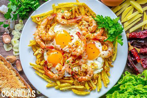 Plato de huevos rotos con gambas al ajillo servido en fuente
