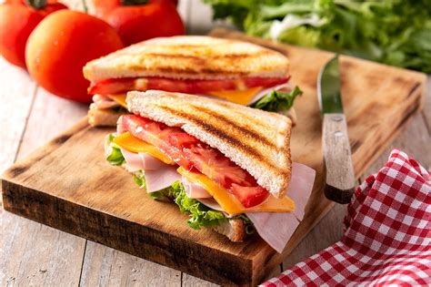 Sándwich de jamón, queso, lechuga y tomate sobre una tabla de madera