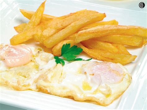 Plato de huevos fritos con patatas paja y trufa rallada