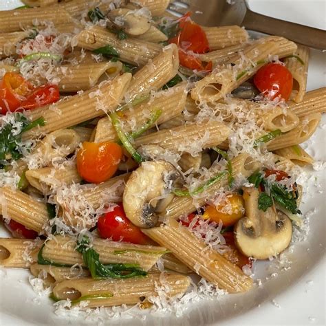 Pasta con espinacas, champiñones y tomate servida en un plato hondo