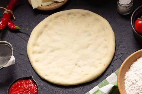 Masa de pizza cruda en forma de bola y estirada, lista para congelar