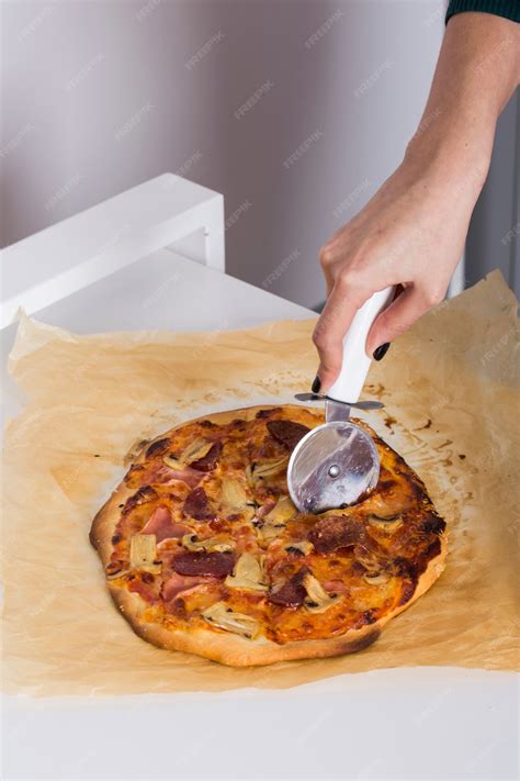 Persona cortando una pizza con un cortador de pizza