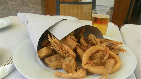 Cartucho de papel con pescado frito en un freidor tradicional