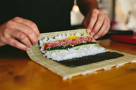 Persona aprendiendo a enrollar sushi en casa con un kit de sushi