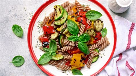 Plato de pasta integral con verduras frescas y proteínas magras