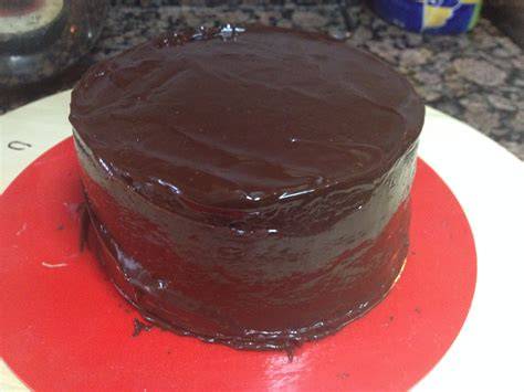 Torta bañada en ganache de chocolate con una espátula