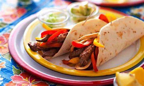 Plato de fajitas con carne y vegetales servidos con tortillas de trigo