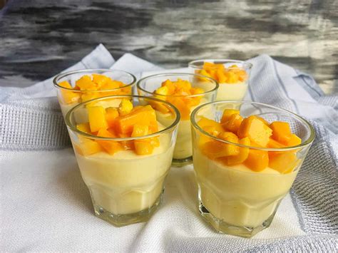 Vasitos de mousse de mango decorados con nata y fresas.