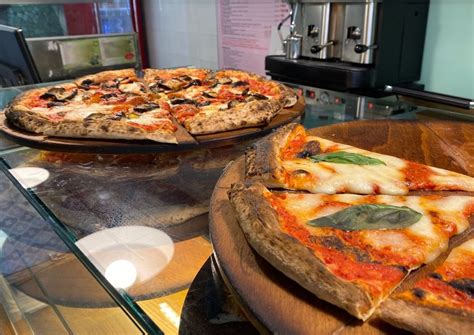 Vitrina de pizzas al corte con diversos ingredientes