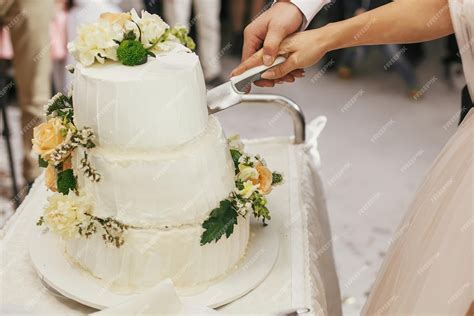 Pareja cortando tarta nupcial con cuchillo y espátula