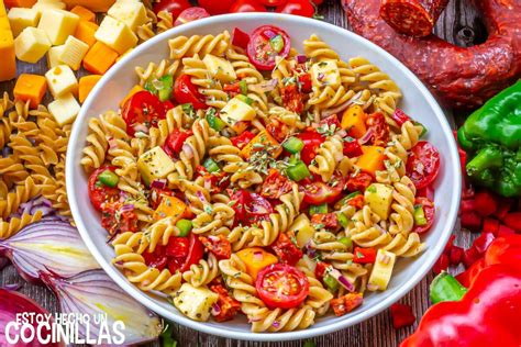 Ensalada de pasta con chorizo servida en un plato, con un vaso de vino