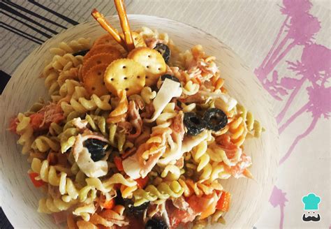 Persona sirviendo ensalada de pasta con salmón y piña en un bol