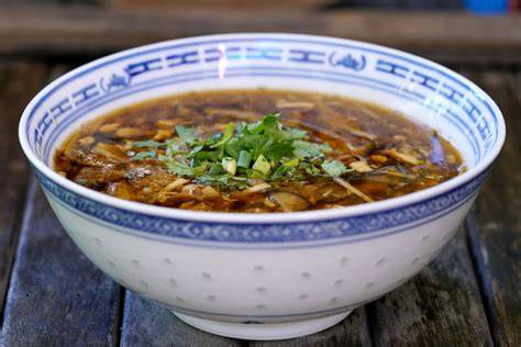 Sopa agripicante servida en un tazón con tofu y setas
