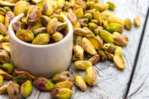 Recipiente con pistachos pelados y tostados sobre una mesa de madera