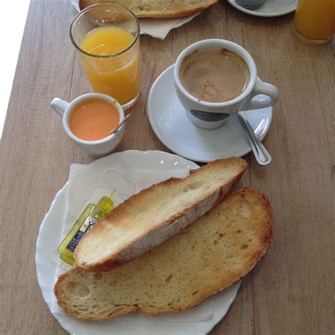 Mesa de desayuno con tostada, zumo y aceite de oliva con vistas al mar