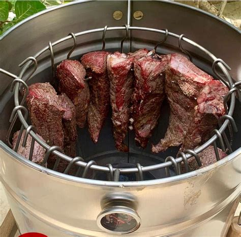 Asado de barril con carne colgando de ganchos