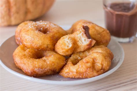 Plato de buñuelos de calabaza recién hechos acompañados de una taza de chocolate