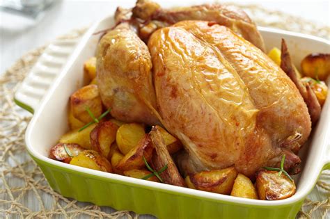 Pollo entero asado con naranjas y patatas en una bandeja de horno