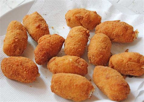 Croquetas doradas y crujientes escurriendo sobre papel absorbente