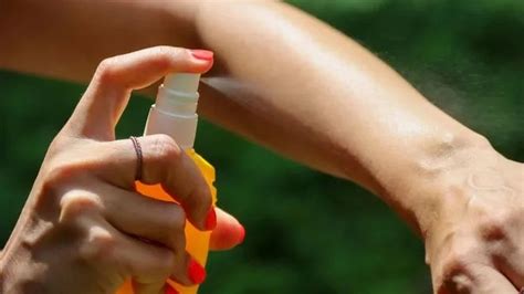 Una mujer rociándose repelente de mosquitos casero en el brazo