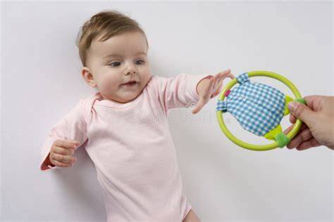 Bebé de 3 meses intentando alcanzar un juguete