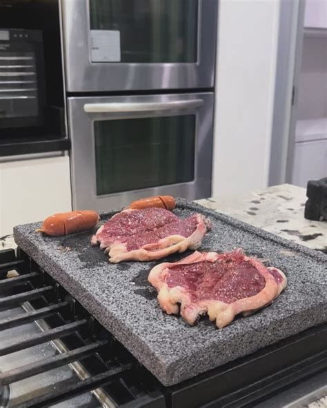 carne de alta calidad cocinándose sobre una piedra volcánica caliente