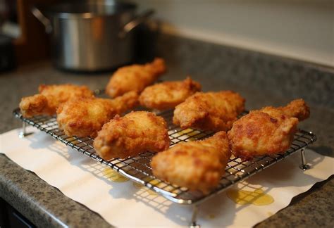 Pollo frito recién salido del aceite escurriendo en una rejilla