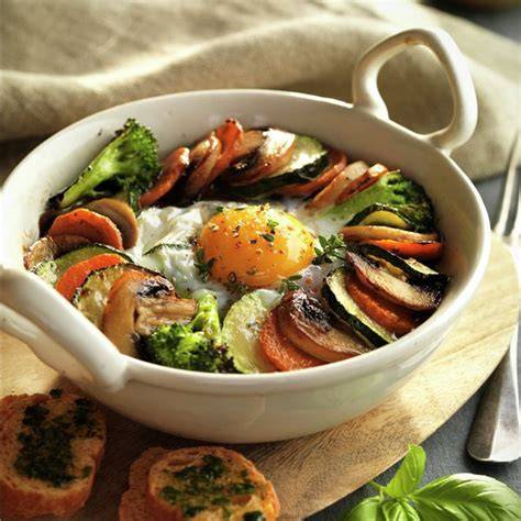 Plato de verduras al horno con huevo y jamón servido en cazuelita