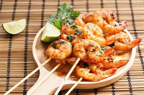Imagen de langostinos siendo ensartados en brochetas.