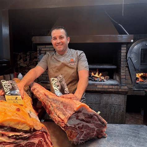 Maestro parrillero de El Huaso cortando carne a la brasa