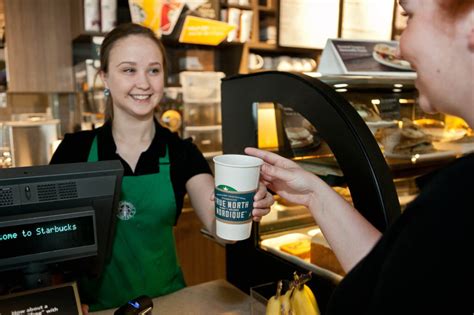 Barista de Starbucks sonriendo y entregando una bebida