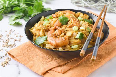 Plato de fideos de arroz fritos caldosos con verduras y gambas