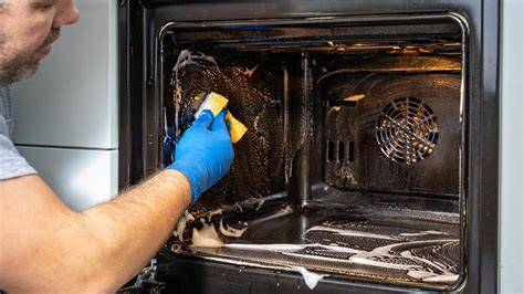 Persona limpiando el interior de un horno eléctrico