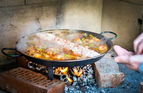 Paella cocinándose a leña en un paellero tradicional.