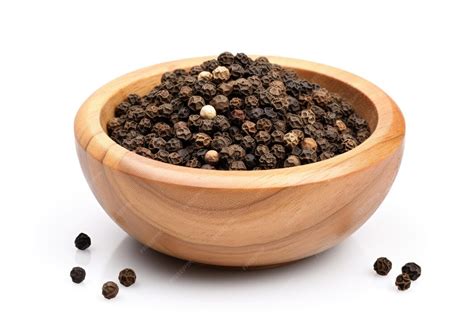 Un cuenco con granos de pimienta de cayena y pimienta negra