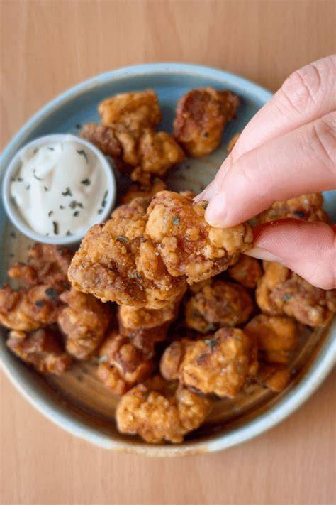 Palomitas de pollo crujientes en un plato con salsa