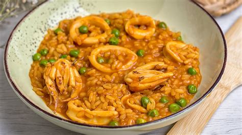 Plato servido de arroz caldoso con calamares y merluza decorado
