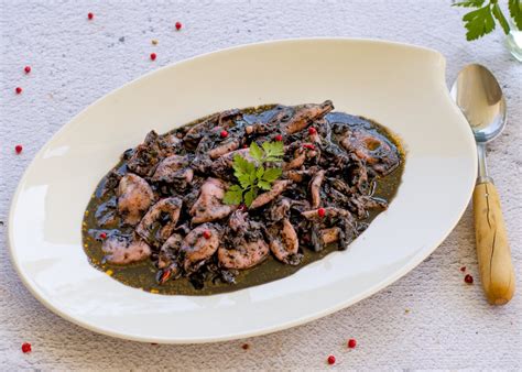 Plato de chipirones en su tinta tradicional servido en cazuela de barro
