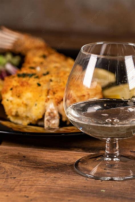 Copa de vino blanco junto a un plato de pescado